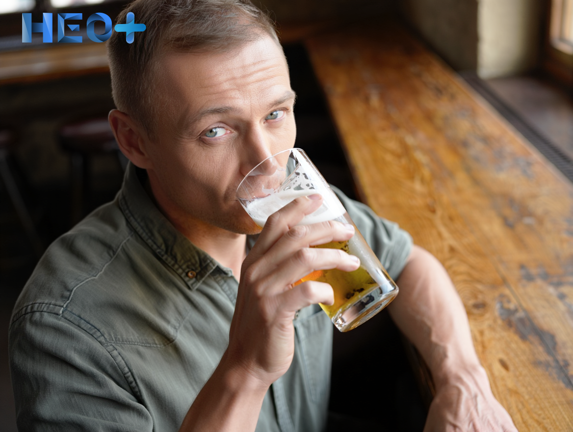 Мужчина сидит за столом и пьет пиво